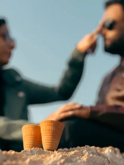 A creative, artistic shot focusing on the two chai cups with the couple blurred in the background. It’s a playful moment that tells the story of their shared love for tea and each other.