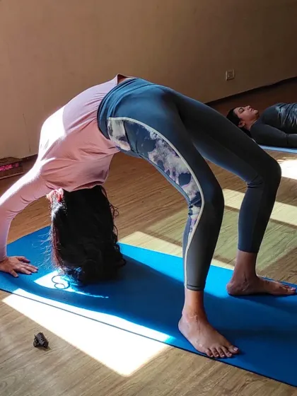 A practitioner holds Urdhva Dhanurasana (Wheel Pose), a powerful backbend that opens the heart and strengthens the entire body. Sunlight streams in, illuminating the energy of the pose.