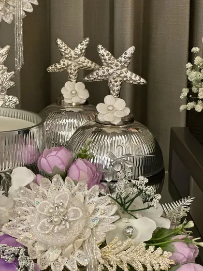 It's all in the details. This close up shows the starfish toppers on our silver jars, surrounded by intricate lace flowers and delicate purple buds. Every element is chosen to create a unique and luxurious feel.