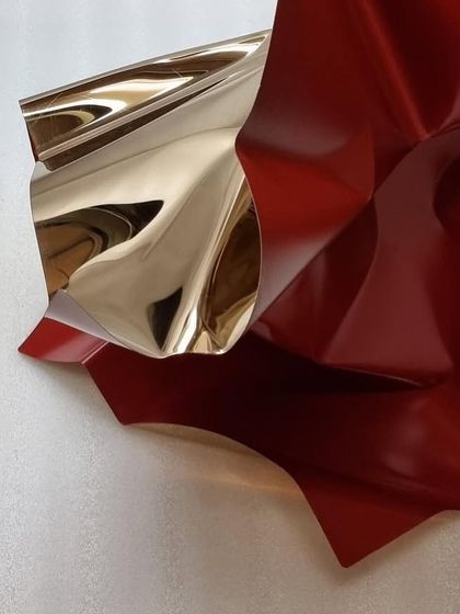 A detail of the red and gold tabletop piece, showing the contrast between the matte red and the reflective gold.