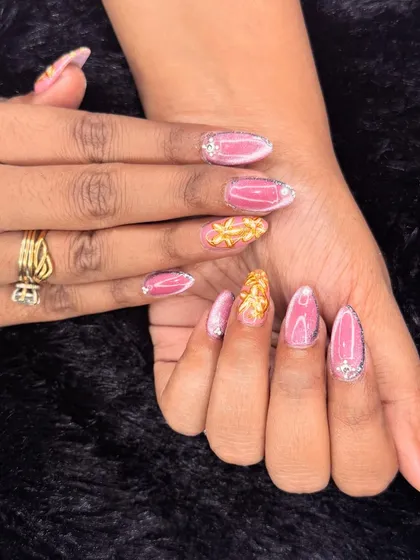 This design is all about pink and gold glamour. It combines a shimmering pink base with textured gold leaf accents and sparkling rhinestones at the cuticle.