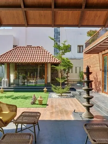 The 'Anandi' house features a central courtyard with a manicured lawn and a separate pavilion, creating a private oasis in an urban setting.