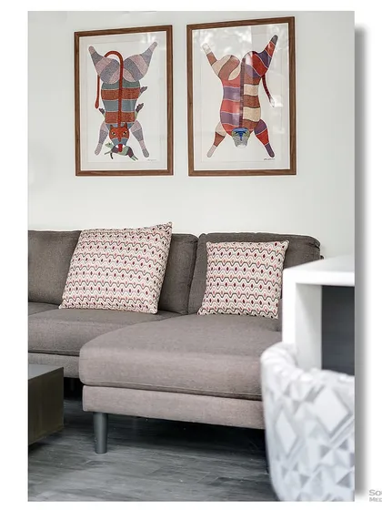 A detail shot of a modern living room inside a container home. The quirky, colorful art depicting stylized tigers adds a playful and artistic touch to the contemporary space.