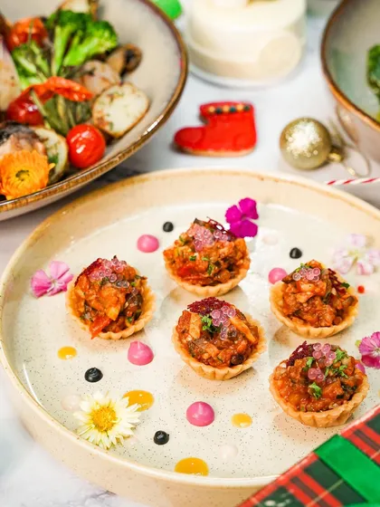 A close-up of delicate savory tartlets, beautifully plated with colorful sauces. This shot highlights the fine details and gourmet quality of the Christmas brunch appetizers.