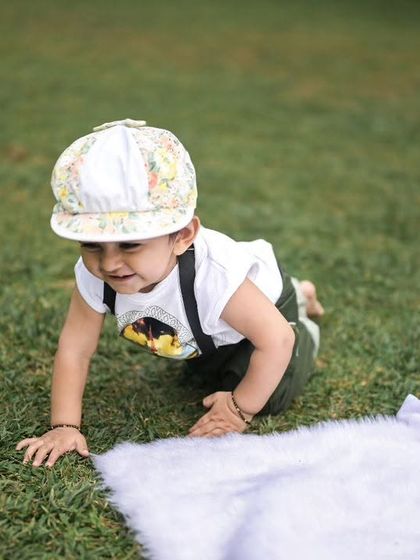 Capturing milestones like crawling is a key part of a baby's first year shoot. This candid shot shows the baby on the move on the soft grass.