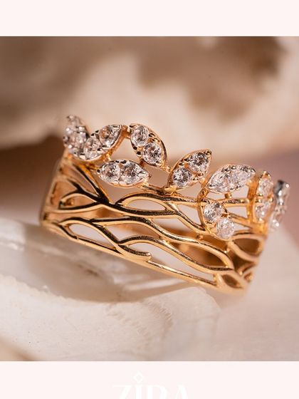 An intricate, nature-inspired ring with diamond-studded leaves on a woven gold band.