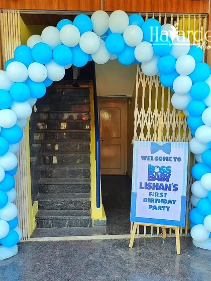 A welcoming balloon arch in blue and white for a Boss Baby first birthday party, complete with a custom welcome sign.