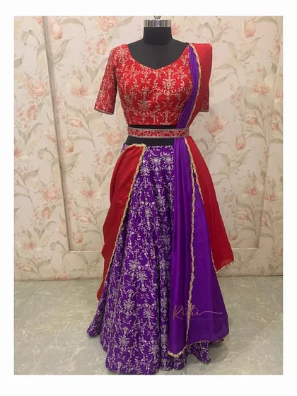 A full view of the custom red and purple half-saree. The ensemble includes a brocade skirt, an embroidered blouse, a draped dupatta, and a matching waistband.