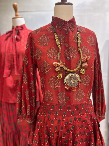 A detailed shot of another red printed top, paired with a statement necklace that complements the rustic charm of the print.