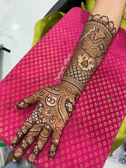 A full-arm engagement mehendi with intertwined rings and other traditional motifs.