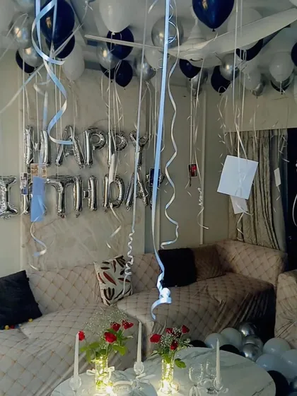 A wider view of the room decoration, showing balloons on the ceiling with hanging ribbons and photos for a personal touch.