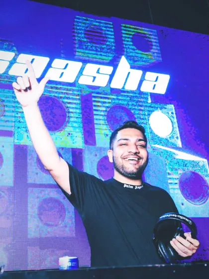 Holding my headphones, ready for the next transition. The vibrant blue lighting and my logo on the screen create a futuristic, high-energy atmosphere.