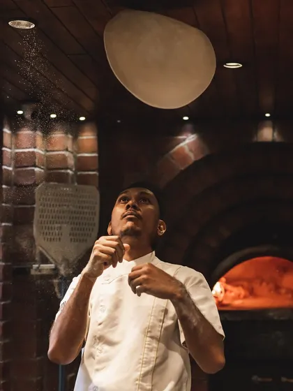 Our chefs are pros who put on a show. Here's one of them in their element, tossing our signature sourdough pizza dough before it hits the oven.