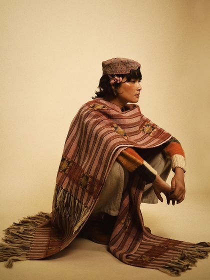 A profile shot that captures a quiet, contemplative mood. The way the shawl drapes creates beautiful lines, emphasizing the craftsmanship of the woven textile.