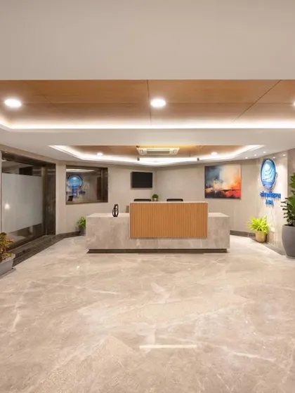 The reception area of a government guest house, designed to feel more like a boutique hotel. The space features marble flooring, wood ceiling panels, and contemporary art.