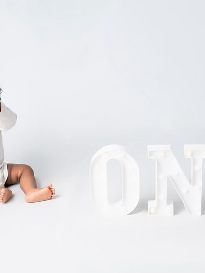 A minimalist first birthday shoot with a simple "ONE" marquee sign.