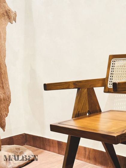The angular beauty of the 'Malben' chair, seen here next to a natural wood sculpture. Its strong lines are crafted from solid teak wood.