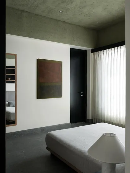 In this son's bedroom, the bed is positioned against a white wall, beneath a dramatic colored ceiling. The furniture is kept simple and low to the ground to create a sense of calm and spaciousness.