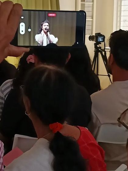 A proud family member records a performance, capturing a special moment.