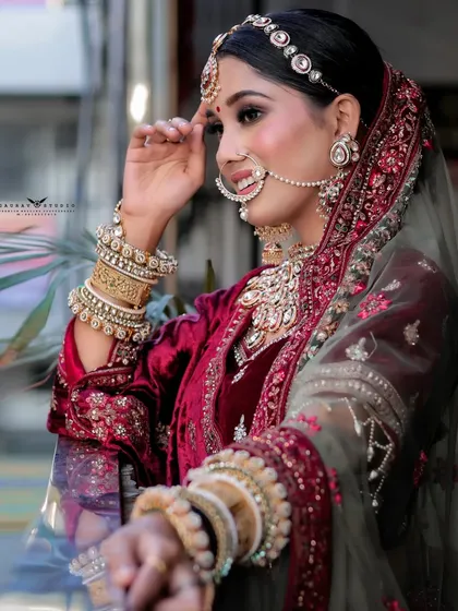 A side profile of the bride, highlighting the heavy embroidery on her velvet outfit and the layers of her jewelry.