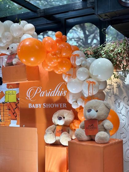 Details from the Hermès-inspired baby shower, featuring teddy bears adorned with the iconic brand's logo and a backdrop of orange gift boxes. It’s luxury meets adorable.