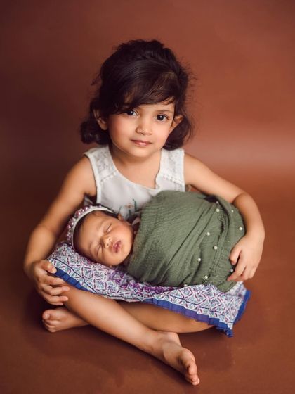A beautiful portrait of two sisters. The older sister's protective and loving gaze is perfectly captured in this studio newborn session.