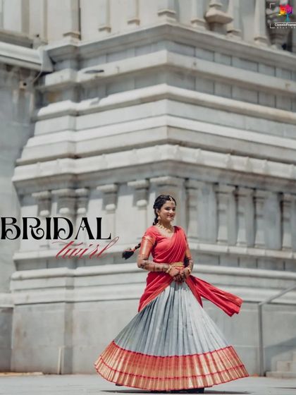 "Bridal Twist." A fun and dynamic shot of the bride twirling in her traditional half saree against a grand temple backdrop. It captures her joyful spirit and the beauty of her outfit.