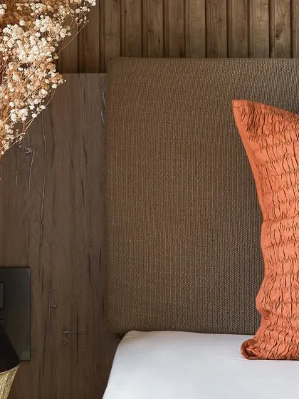 A close-up of the decor in the guest room, showing the textures of the burnt orange pillow and dried flowers.