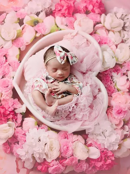 Just like a doll. This beautiful baby girl is surrounded by all sorts of pinks, creating a wonderfully floral and feminine portrait.