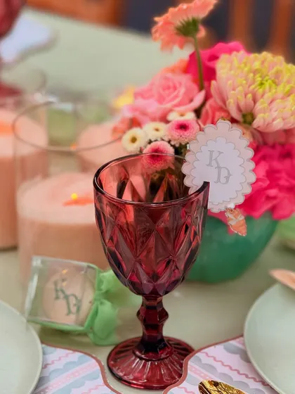 A beautiful shot of the tablescape, highlighting the monogrammed "KD" tag on the glass, a personalized favor, and the vibrant floral centerpiece.
