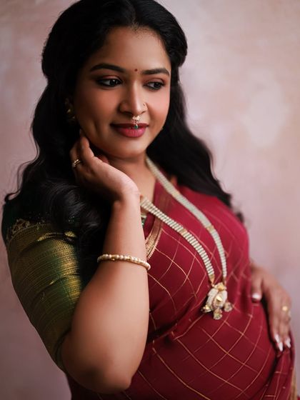 A close-up portrait allows us to focus on the radiant glow of the mother-to-be. Her gentle smile and traditional jewelry add so much beauty to this shot from her Indian maternity shoot.