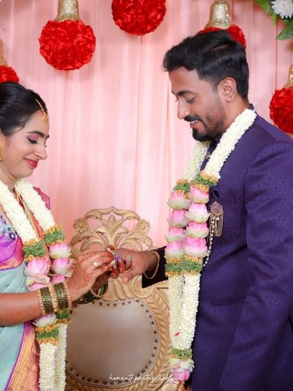 The key moment of the ring exchange during an engagement ceremony, capturing the bride placing the ring on the groom's finger.