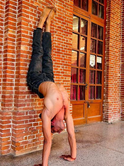 A handstand variation against a wall, focusing on opening the thoracic and lumbar spine.
