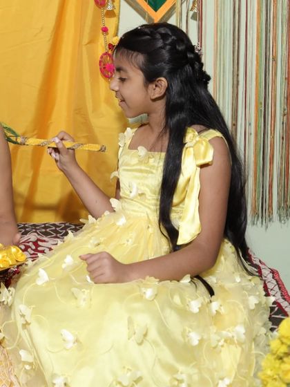 Even the little ones can join the fun! A young girl dressed in a beautiful yellow butterfly-themed gown, perfect for a Haldi function.