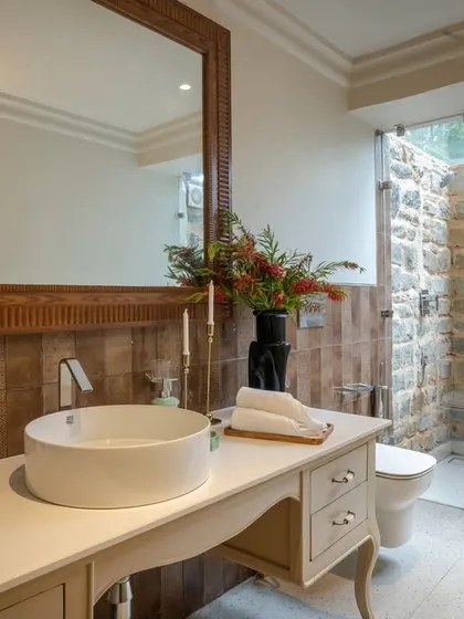 A beautifully balanced bathroom design, where the rustic charm of the local stone shower wall is paired with a clean, white vanity and contemporary vessel sink. It's a perfect blend of modern comfort and natural materials.