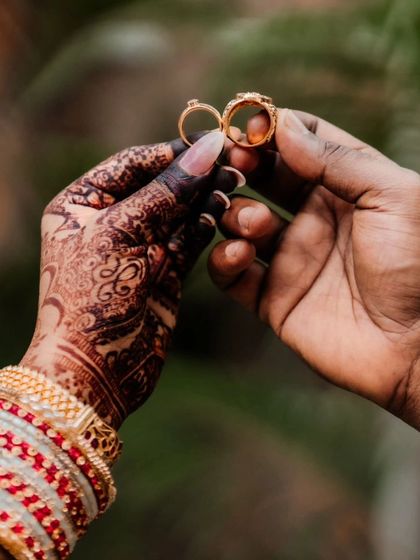 A classic wedding shot, with the couple holding their rings, and the bride's henna on full display.
