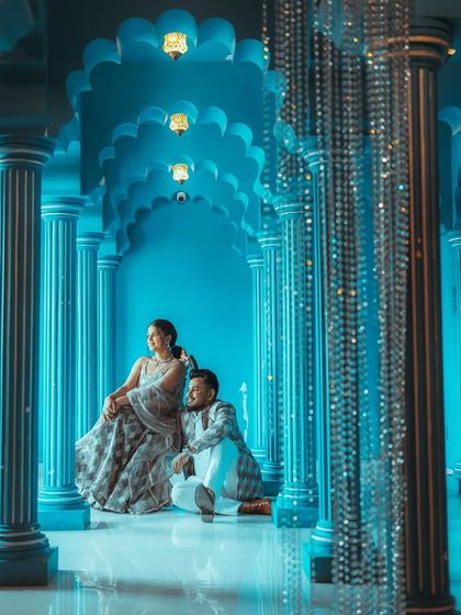 A regal portrait in a stunning blue hall, framed by shimmering crystal curtains. The unique color palette and lighting create a magical, almost surreal atmosphere for this elegant pre-wedding photo.