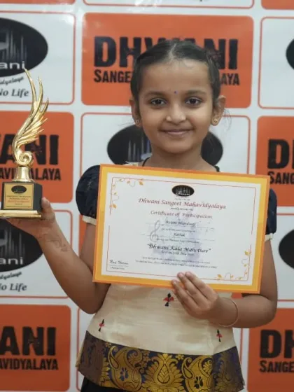 A young student proudly holds her certificate and trophy.