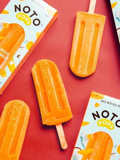 A clean, graphic composition against a bold red background makes these mango-coconut ice pops look incredibly refreshing. The repetition of the product and packaging creates a strong visual rhythm.