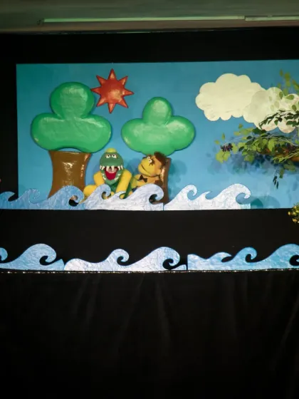 The full stage setup for 'The Monkey & The Crocodile', showing the river scene where the two friends meet. The show teaches an important moral lesson about friendship.