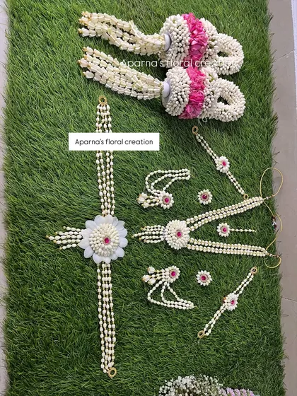 This baby shower set includes a beautiful bajuband, kamarband, and delicate kalire. The pieces are made from jasmine buds with pink and white floral accents.