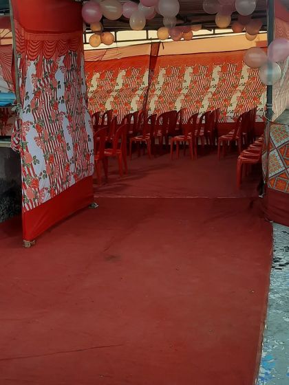A simple pandal setup with red carpet and red plastic chairs. This is a practical and affordable option for many events.