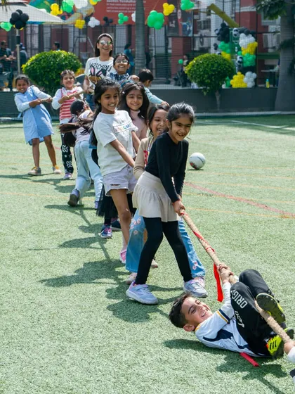 A fun, candid shot of kids and adults playing a lively game of tug-of-war on the grass.