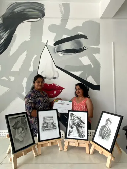 An instructor congratulates a student on completing her sketching course, with her four detailed drawings on display.