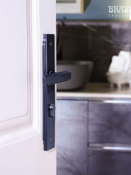 The Natali lever handle on a door leading to the kitchen. The bold, black hardware acts as a unifying design element throughout the different spaces of the home.