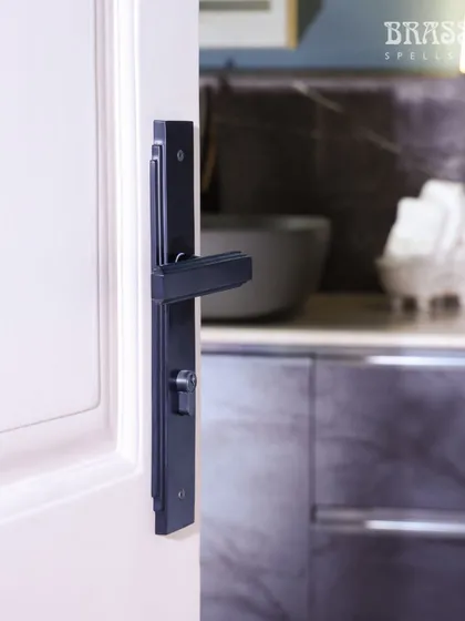 The Natali lever handle on a door leading to the kitchen. The bold, black hardware acts as a unifying design element throughout the different spaces of the home.