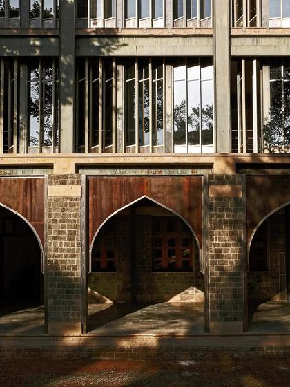 A facade detail showing a combination of deep-set arched openings and vertical fins. This design uses the building's own mass and form to create shade, a timeless strategy for climate control in hot climates.