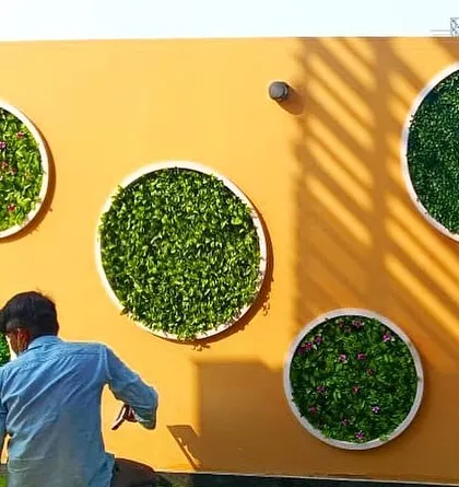This photo shows my team member during the installation of circular green wall panels. This design is a great way to break up a large, monotonous wall and add artistic, nature-inspired elements to a space.