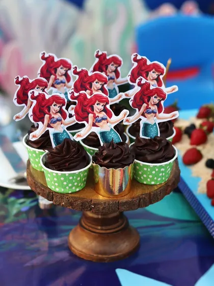 The Ariel cupcakes displayed on a rustic wooden stand.