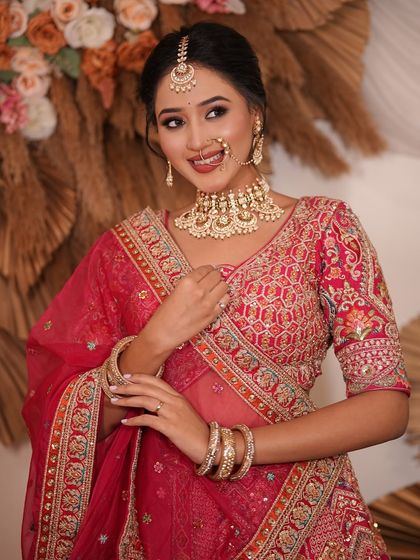 A close-up of a model in a red lehenga, highlighting the intricate gold jewellery. This shows the quality and detail you get with my rentals.